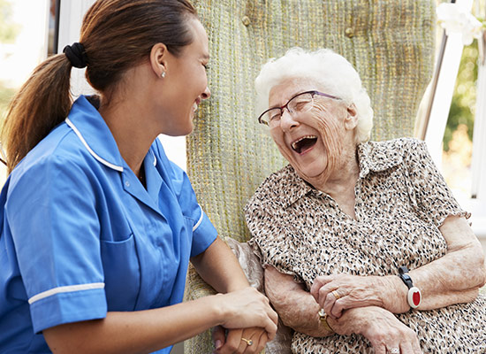 Senior citizen laughing with a nurse